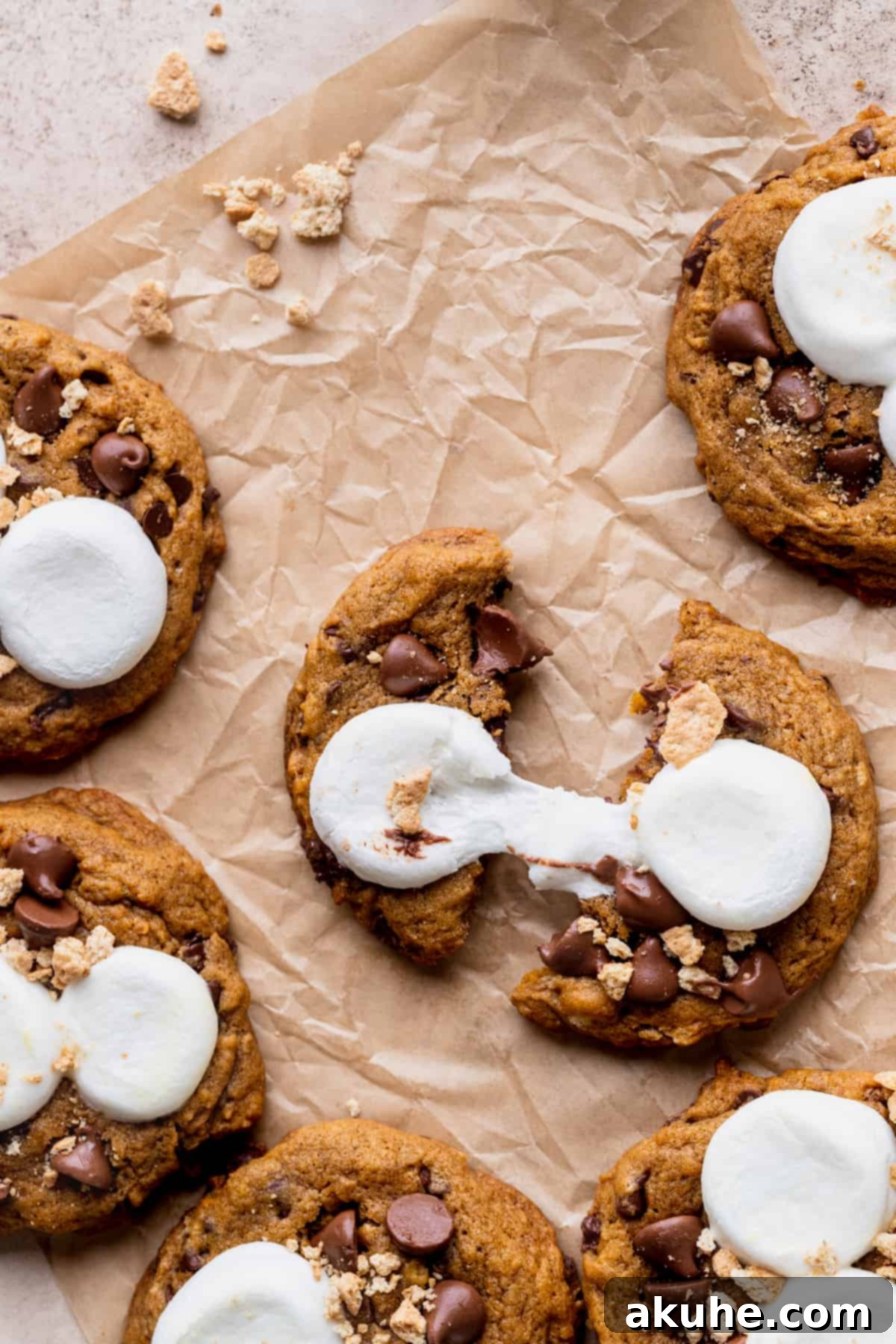 Pumpkin S'mores Cookies 9 A hand pulling apart a pumpkin s'mores cookie, showing the gooey marshmallow stretch.