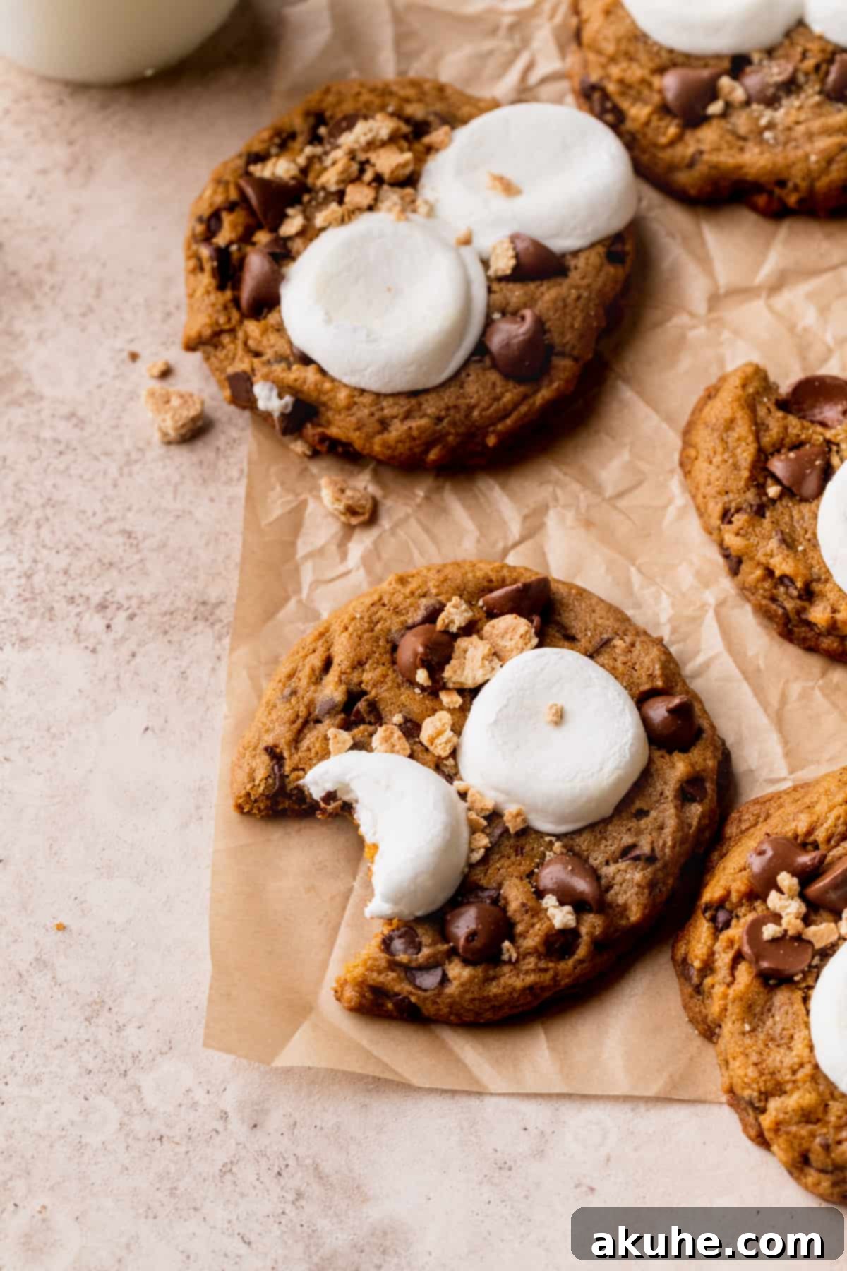 Pumpkin S'mores Cookies 10 A pumpkin s'mores cookie with a bite missing, revealing its soft interior.