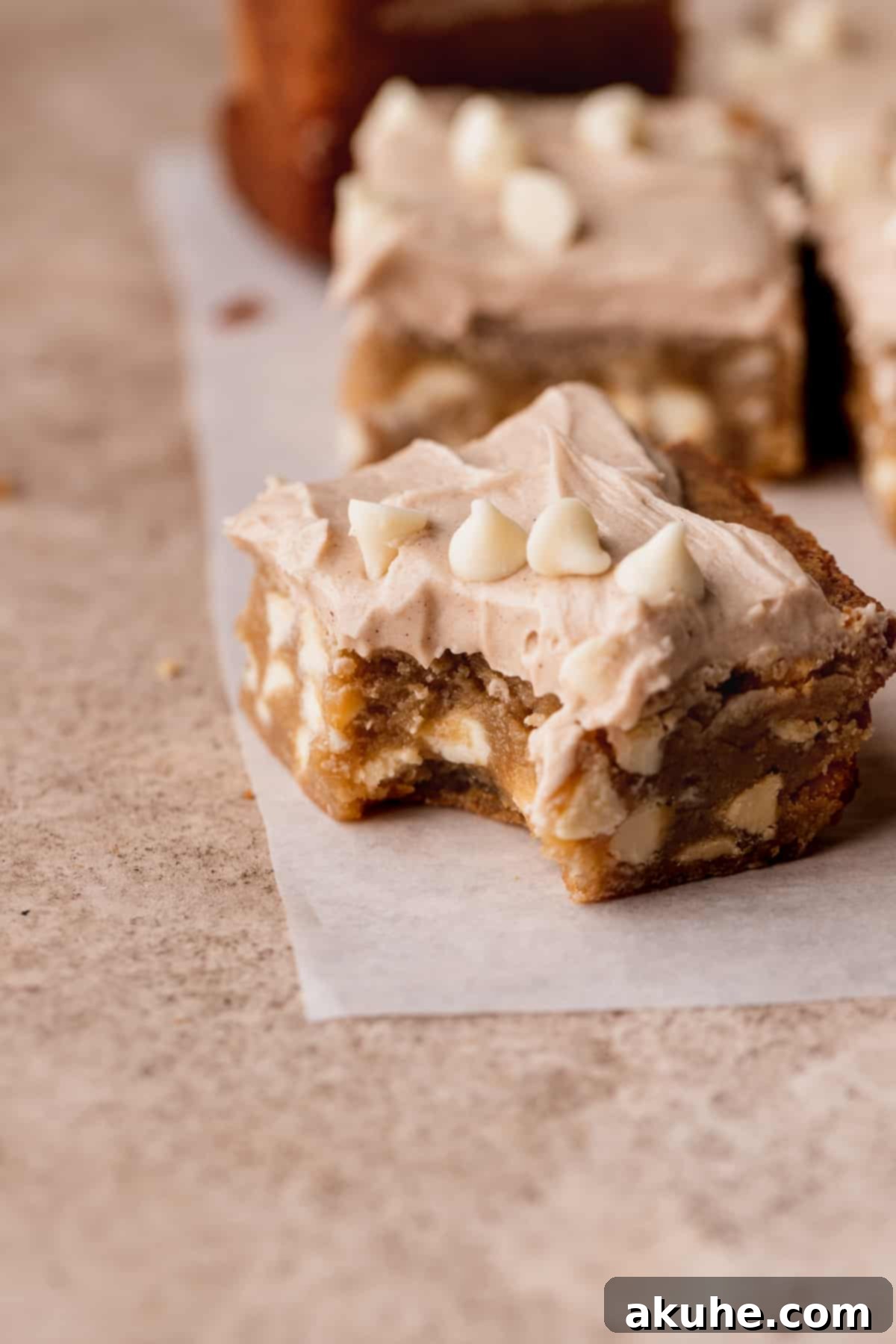 A delectable White Chocolate Cinnamon Blondie with a bite missing, showcasing its gooey interior.