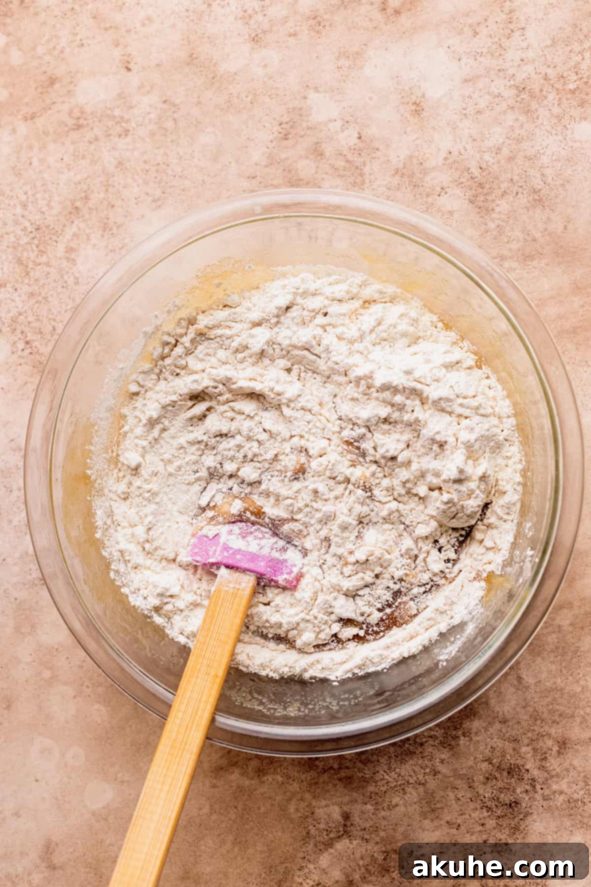 Dry ingredients being added to the wet mixture in a bowl.