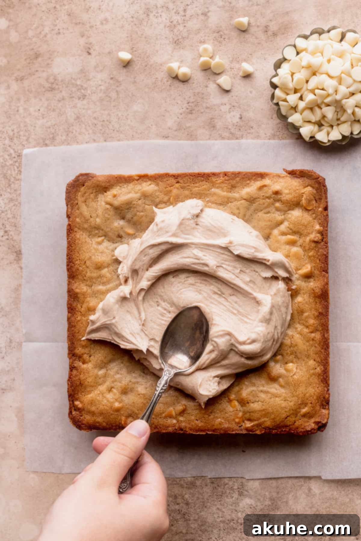 Spreading smooth cinnamon cream cheese frosting generously over the cooled blondies.