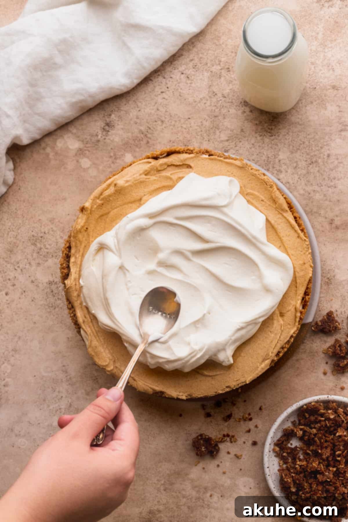 Marbled No Bake Pumpkin Cheesecake 14 Spreading whipped cream on top of cheesecake.