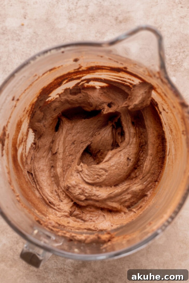 Decadent Oreo Brownie Cookies 5 Wet ingredients including melted chocolate and beaten eggs in a mixing bowl, showcasing a lightened, aerated texture.