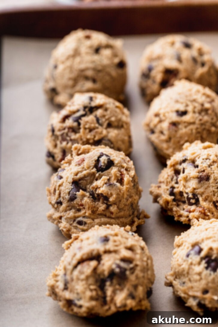 Toasted Pecan Chocolate Chip Delights 8 Evenly scooped cookie dough balls arranged on a parchment-lined baking sheet, ready for the oven.