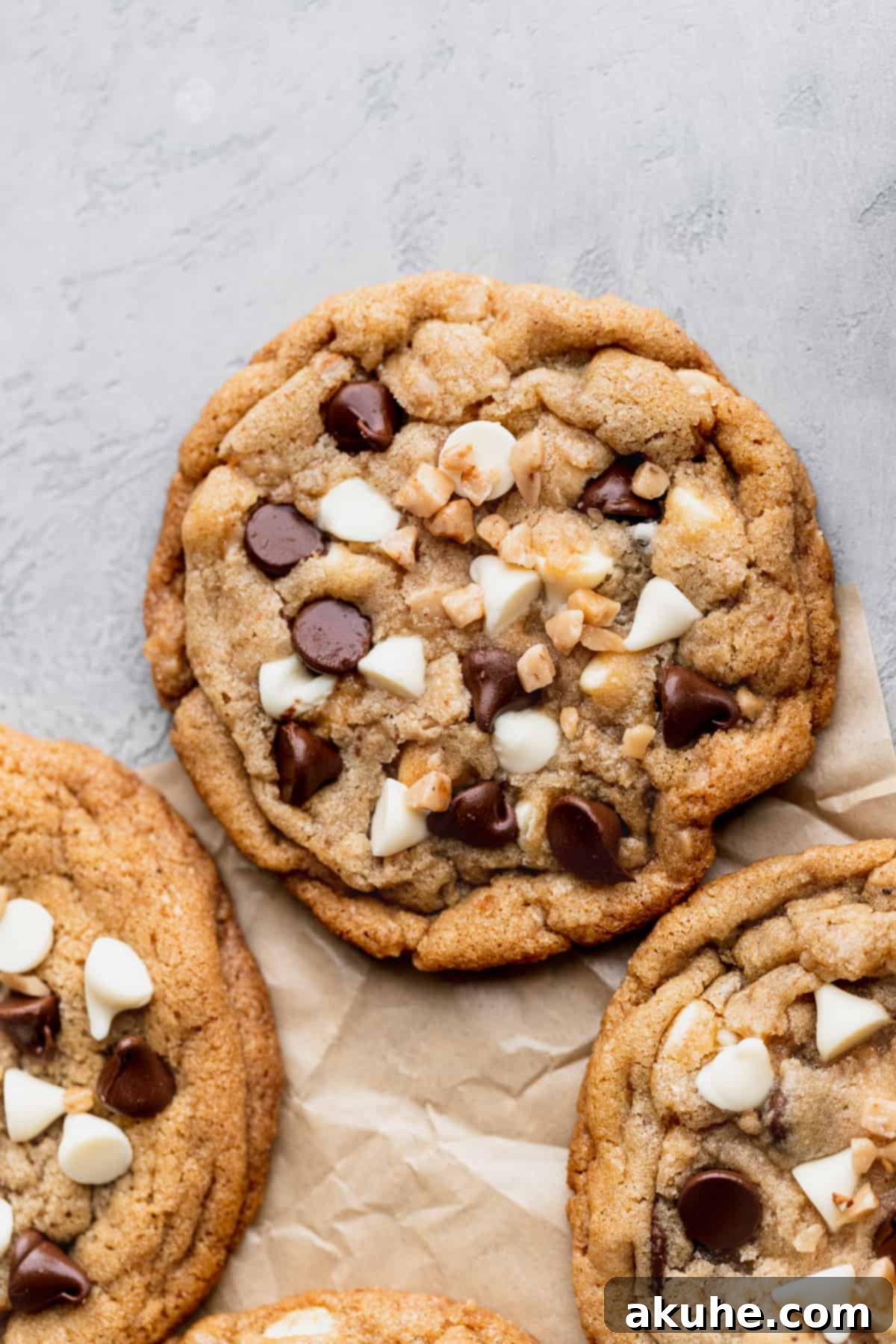 Decadent White Chocolate Toffee Cookies 12 A single white chocolate toffee cookie resting on a parchment-lined baking sheet.