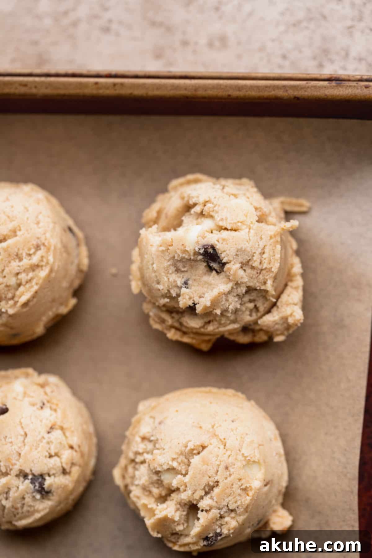 Decadent White Chocolate Toffee Cookies 10 Scooped cookie dough balls arranged on a parchment-lined cookie sheet.