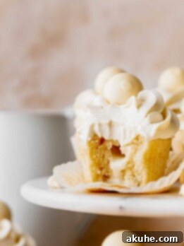 Decadent White Chocolate Cupcakes 12 White chocolate truffle cupcakes with a bite missing on a cake stand.
