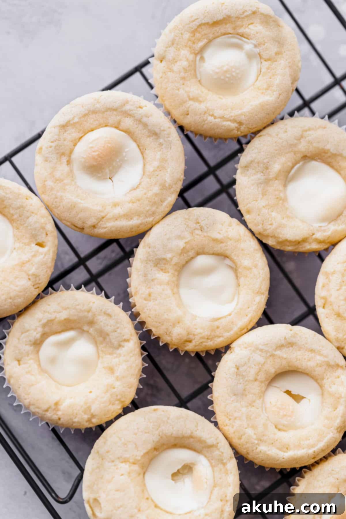 Decadent White Chocolate Cupcakes 8 Freshly baked cupcakes cooling on a wire rack, each with a white chocolate truffle gently pressed into the top.