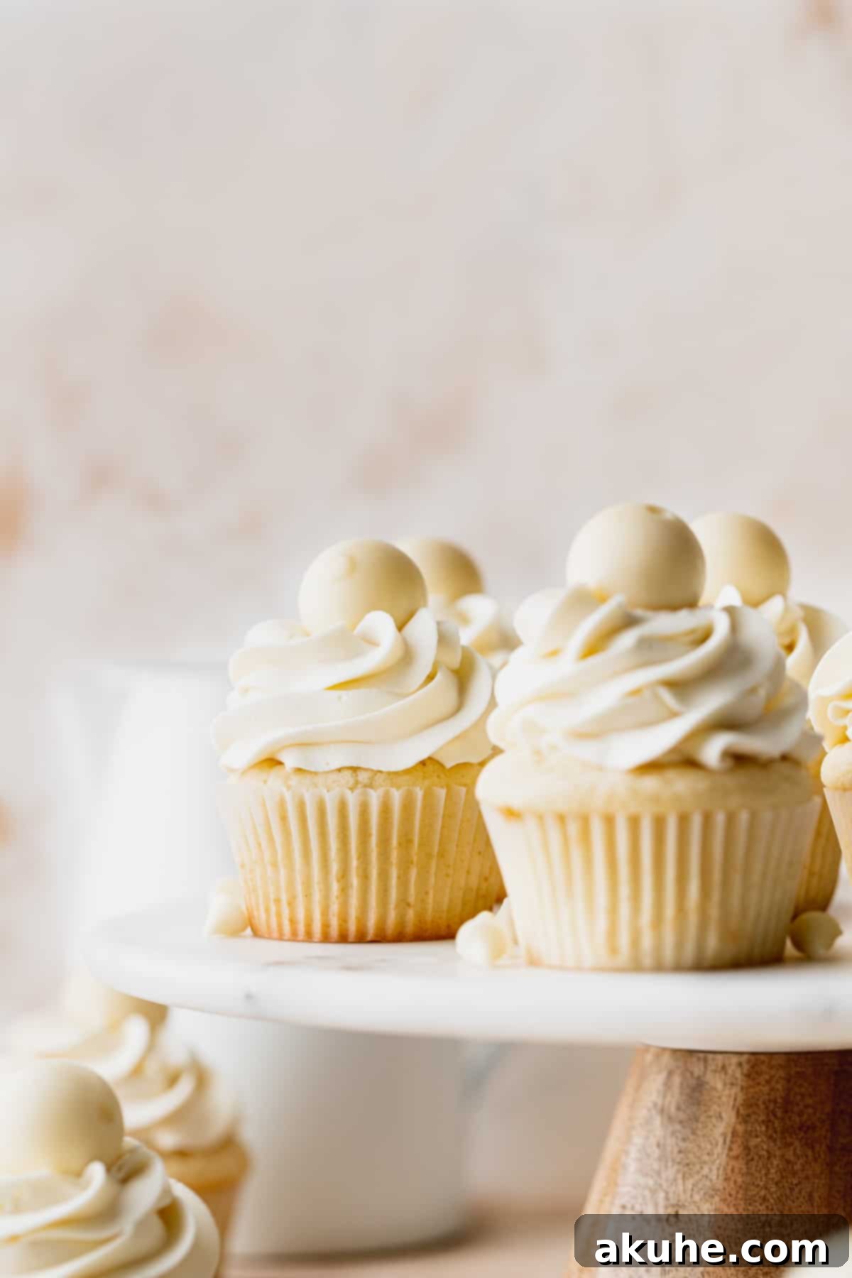 Decadent White Chocolate Cupcakes 9 A close-up view of beautifully frosted white chocolate truffle cupcakes, showcasing their smooth texture and elegant piping, on a cake stand.