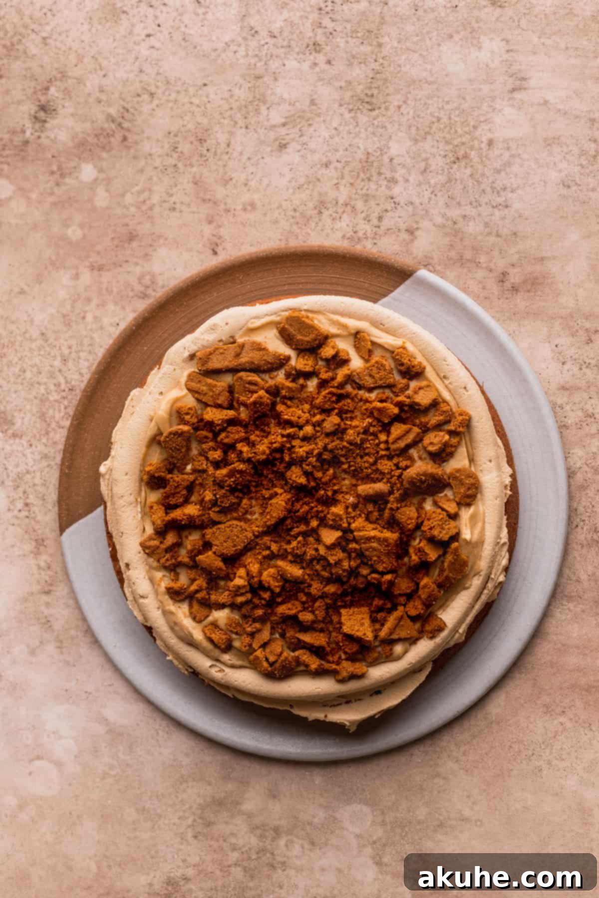 Close-up of chopped Biscoff cookies sprinkled over a layer of filling, adding crunch and flavor.