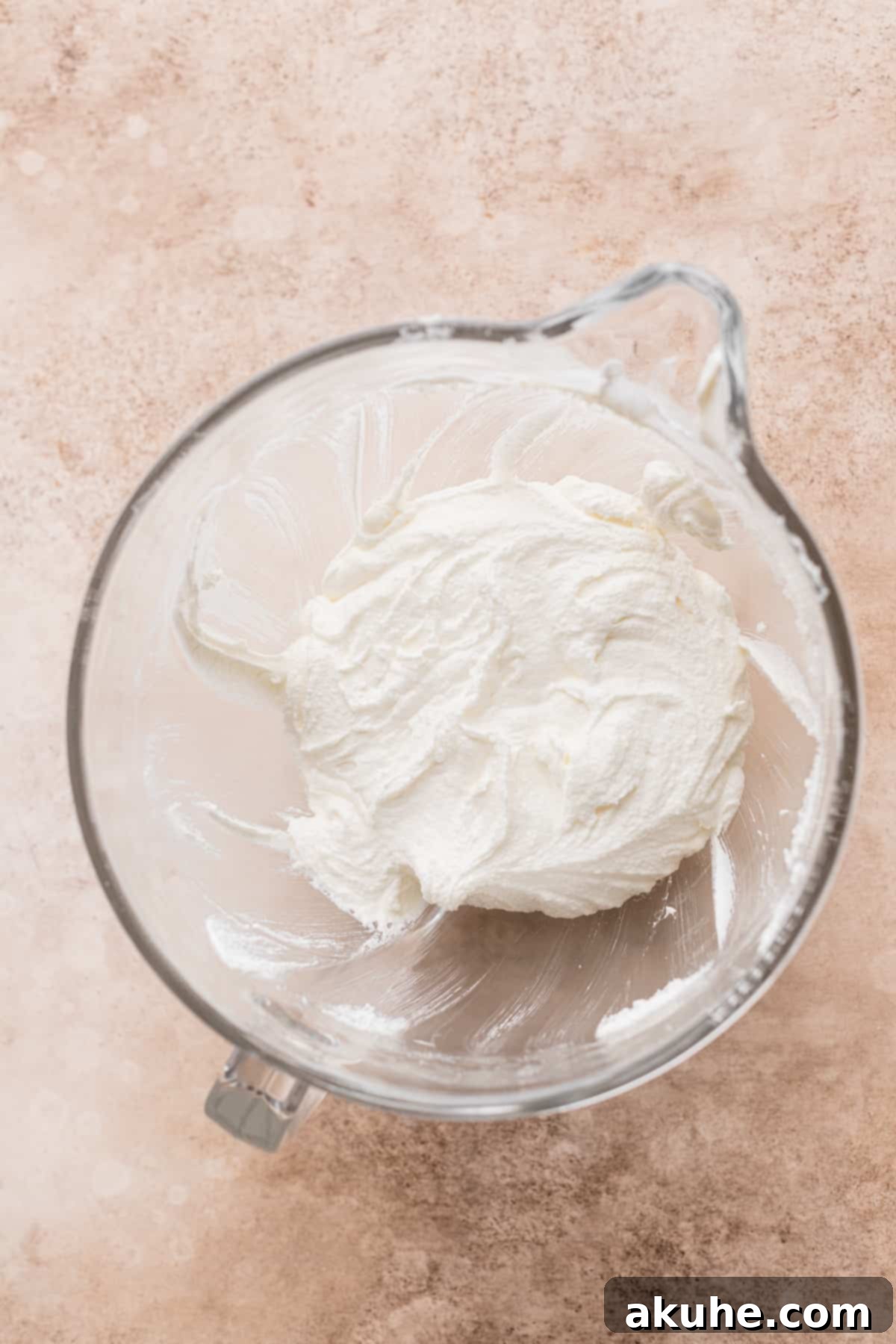 Close-up of butter and sugar being whipped to a pale, fluffy consistency in a mixing bowl.