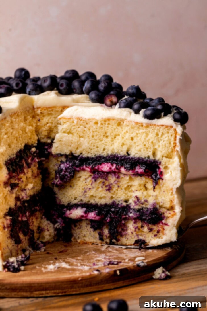 Blueberry Bliss Cake 2 A delectable slice being taken out of the moist 3-layer vanilla blueberry jam cake, revealing its rich filling and creamy frosting.