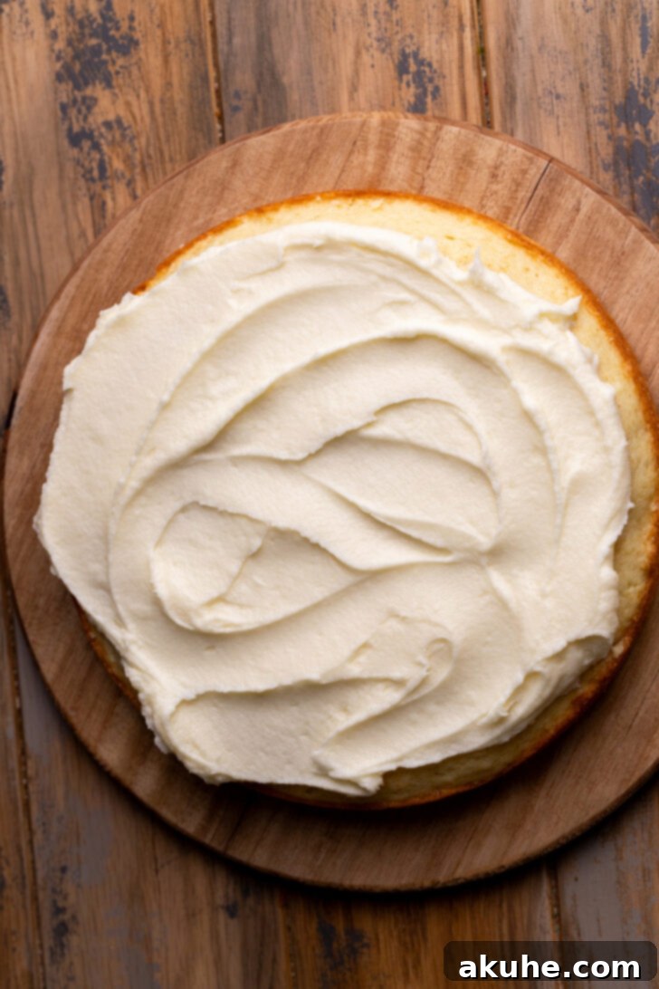 Blueberry Bliss Cake 9 Creamy frosting spread evenly on a cake layer, with a piped border around the edge, creating a dam for the jam.