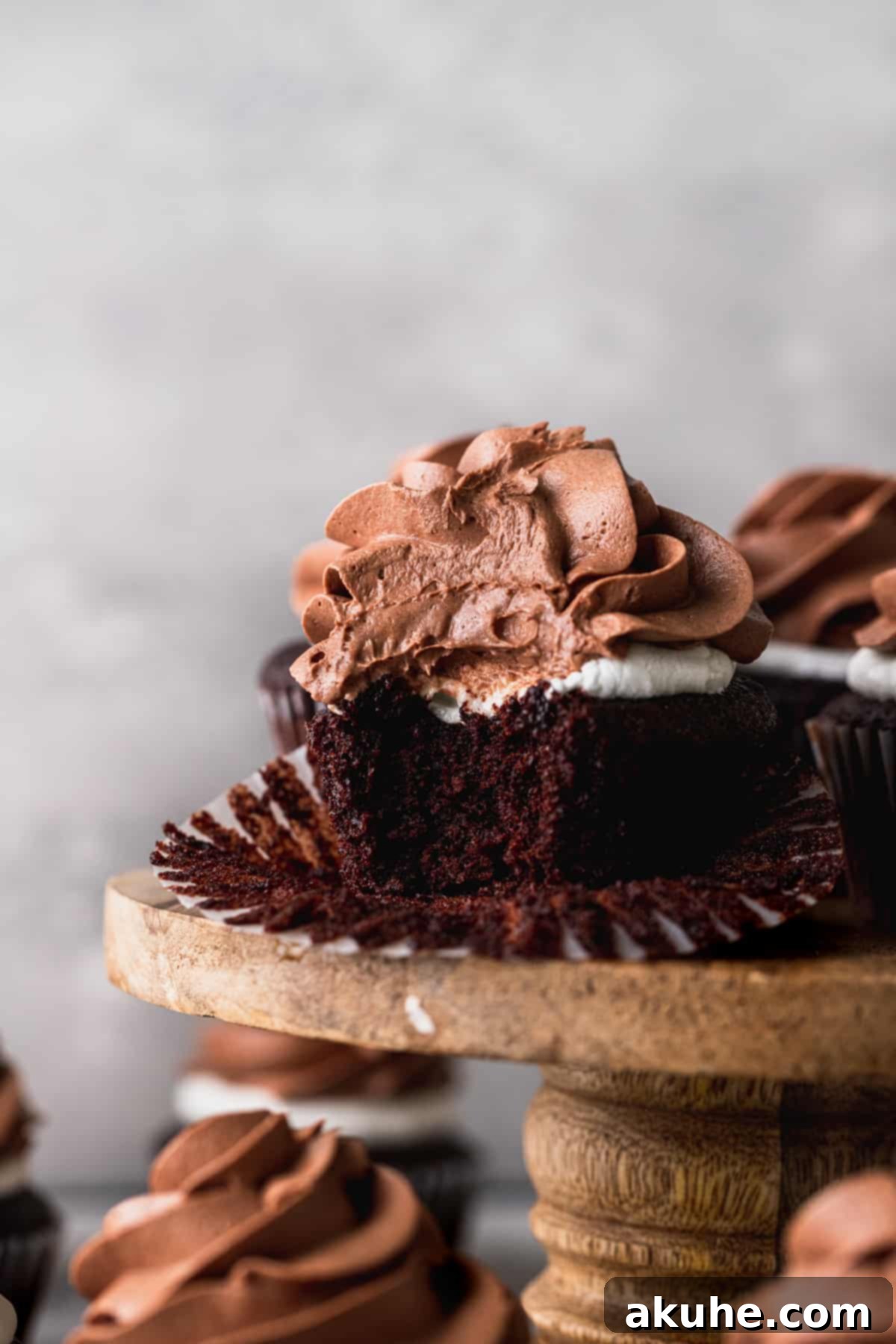 Bite missing from a hot chocolate cupcake, revealing its moist interior and marshmallow topping.
