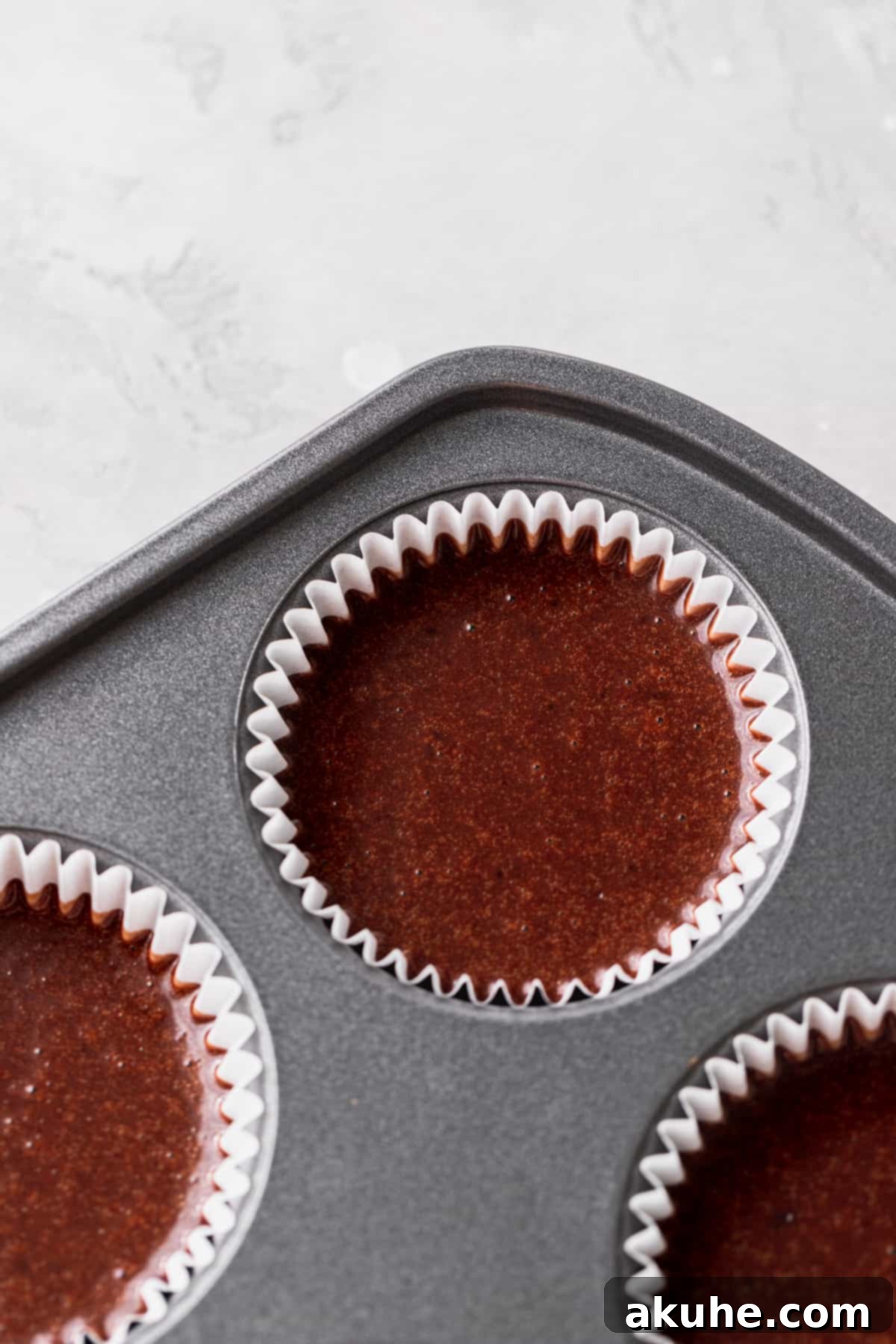 Cake batter precisely portioned into a cupcake pan.