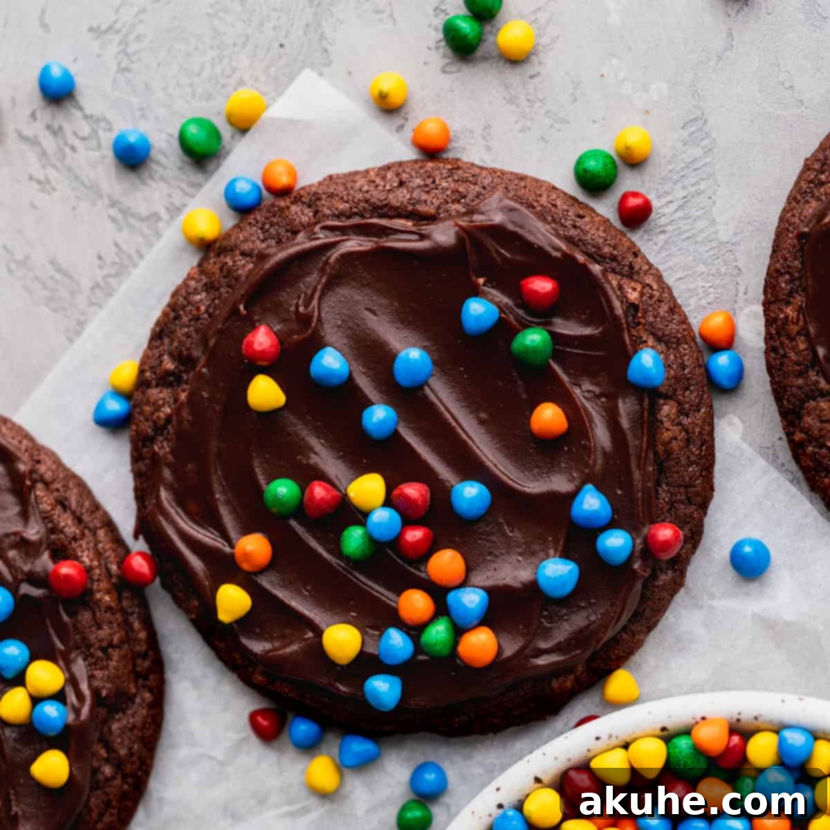 Deep Space Fudge Cookies 2 A single, perfectly baked Cosmic Brownie Cookie with colorful sprinkles, resting on parchment paper, showcasing its rich chocolate ganache topping.