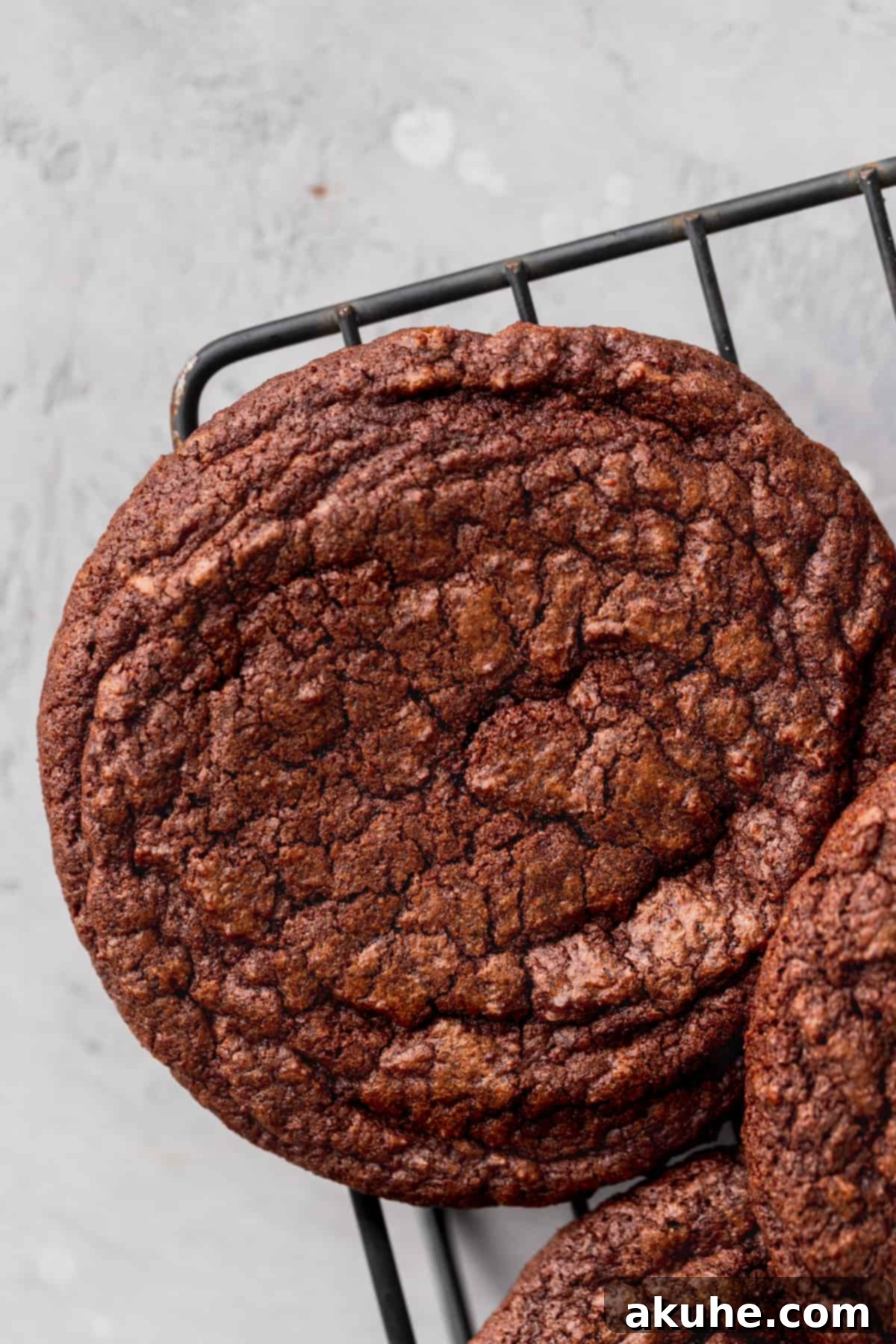 Deep Space Fudge Cookies 9 A freshly baked, dark chocolate brownie cookie cooling on a wire rack, perfectly shaped and ready for its ganache topping.