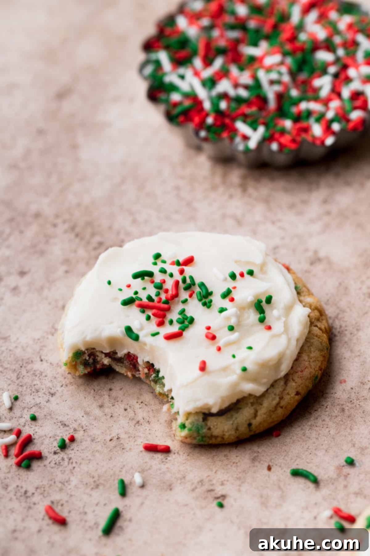 Merry & Bright Sprinkle Cookies 3 A Christmas sprinkle cookie with a bite taken out, revealing its soft, sprinkle-filled interior and creamy frosting.
