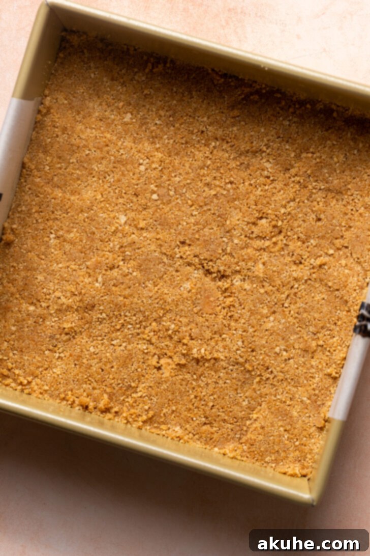 Strawberry Cheesecake Squares 4 Graham cracker crust being pressed into the bottom of a pan.