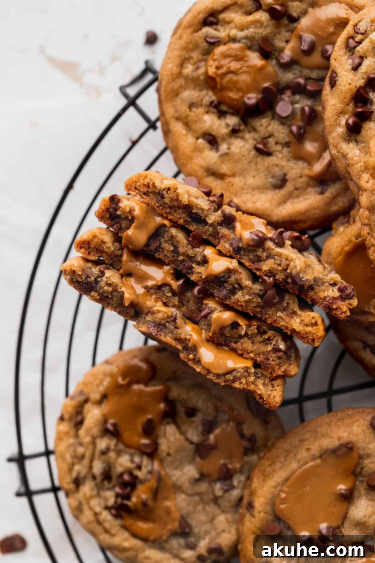 A Biscoff butter cookie split in half on a wire rack, revealing its soft, chewy interior filled with chocolate chips and cookie butter.