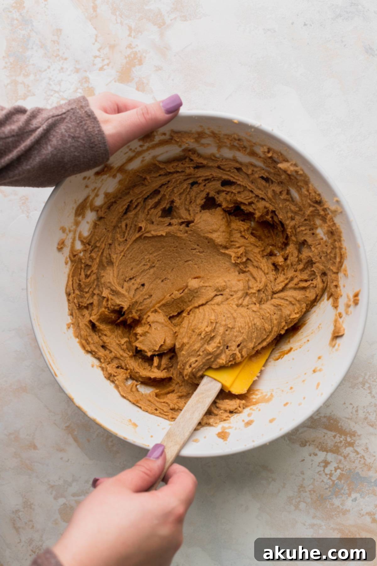 Close-up of butter and Biscoff cookie butter being mixed in a bowl, creating a smooth, creamy texture.
