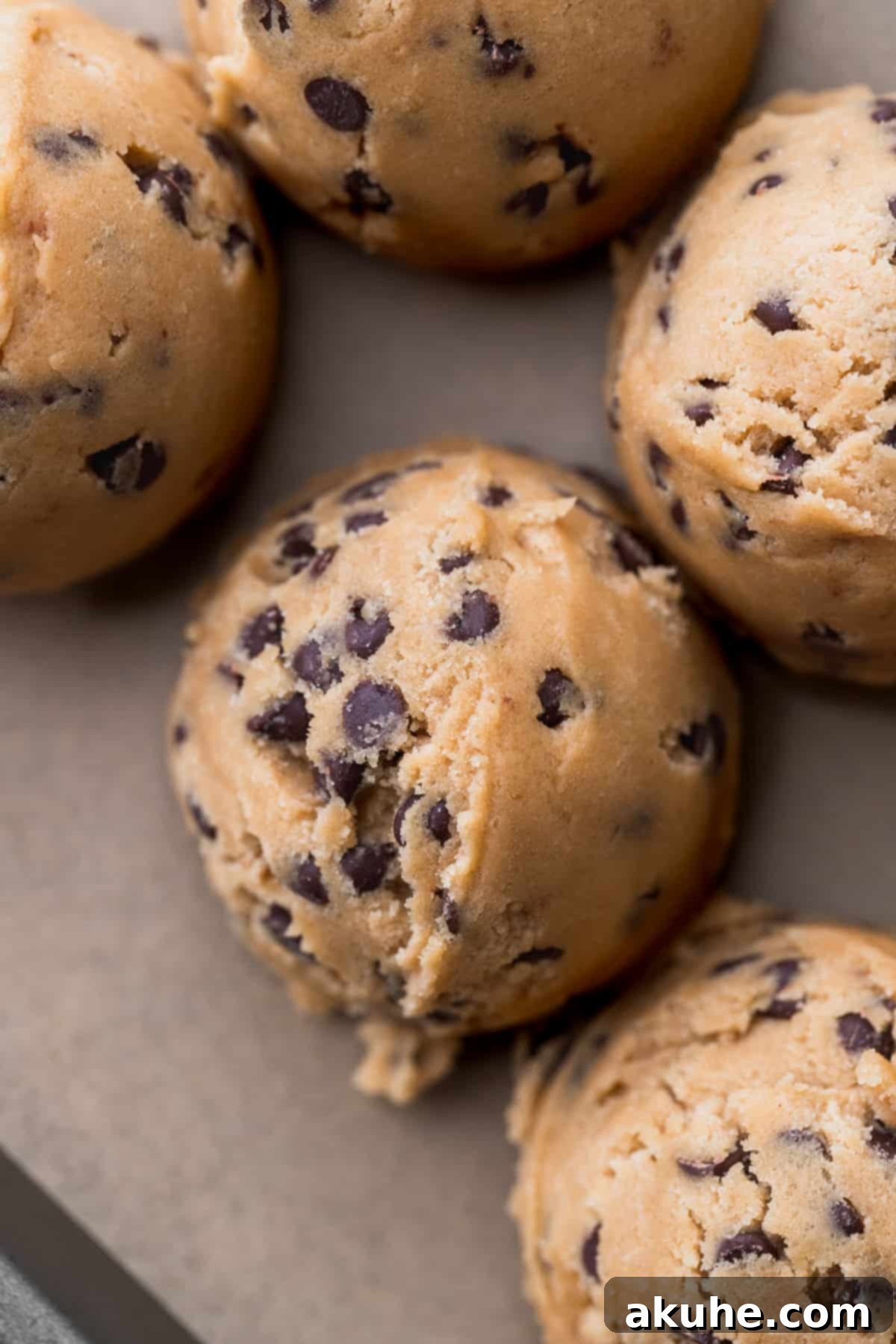 Perfectly scooped cookie dough balls, ready for baking on a parchment-lined cookie sheet.