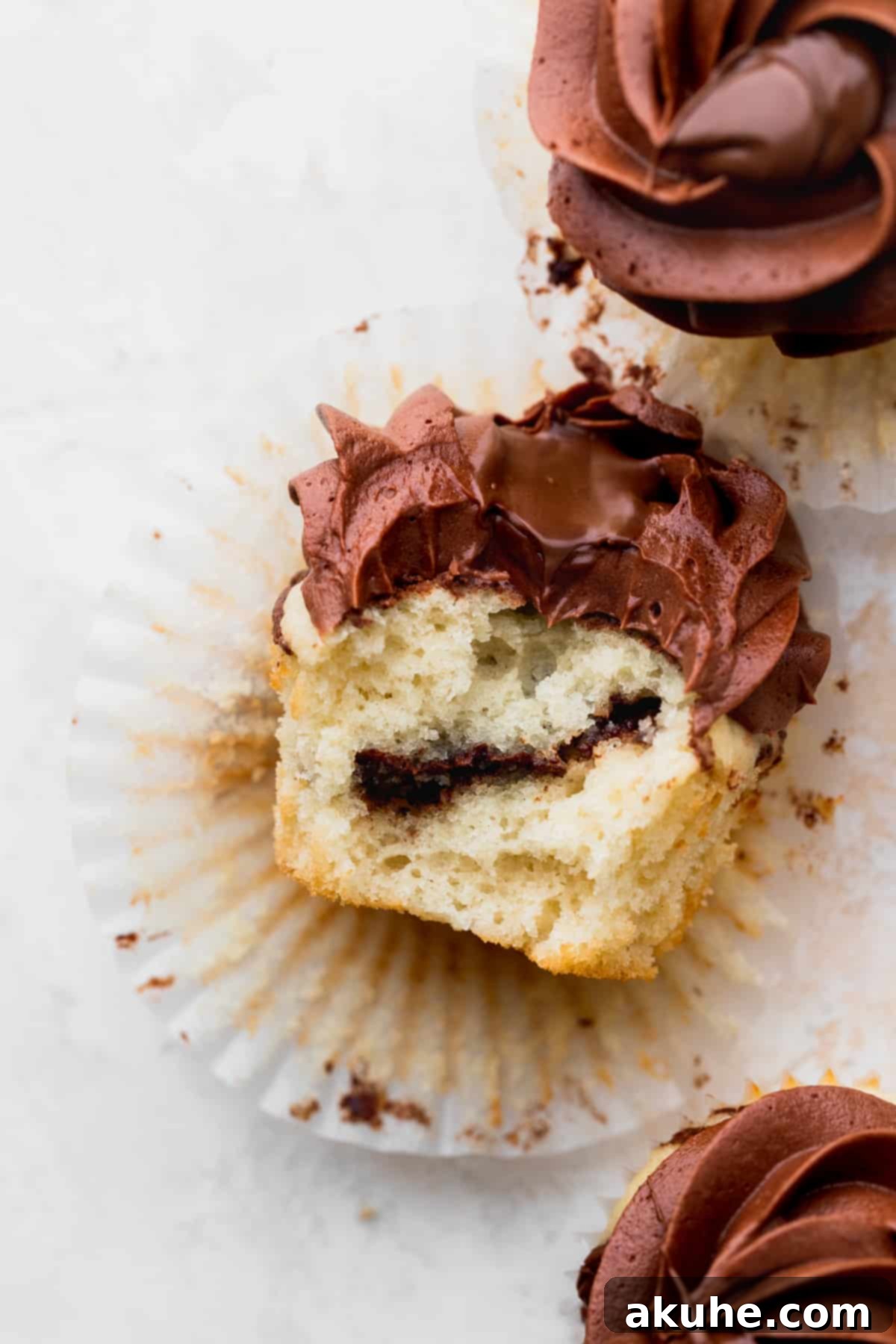 Irresistible Vanilla Nutella Cupcakes 2 A perfectly baked vanilla Nutella cupcake with a bite taken out, revealing the creamy Nutella swirl inside.