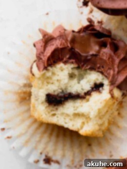 Irresistible Vanilla Nutella Cupcakes 13 A delicious homemade vanilla Nutella cupcake with a bite taken, showcasing the creamy Nutella swirl inside.