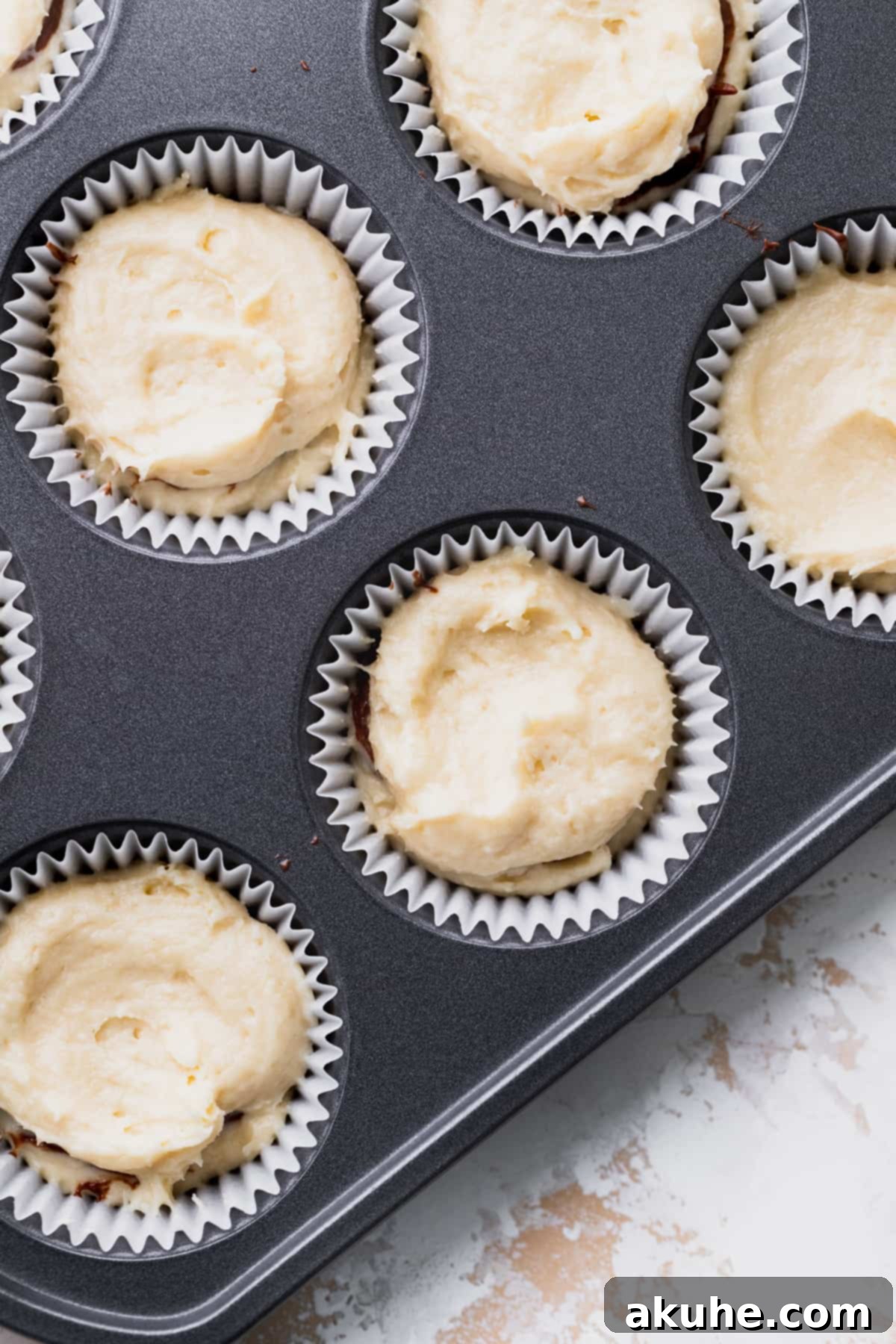 Irresistible Vanilla Nutella Cupcakes 6 Cupcake batter filled into muffin tin liners, layered with Nutella and now ready for baking.