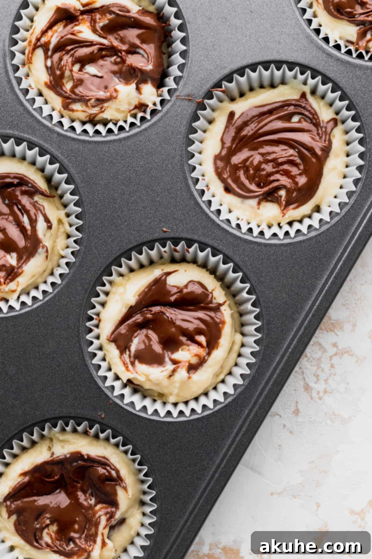 Irresistible Vanilla Nutella Cupcakes 7 The final layer of Nutella gracefully swirled on top of the cupcake batter, creating an appealing pattern before baking.