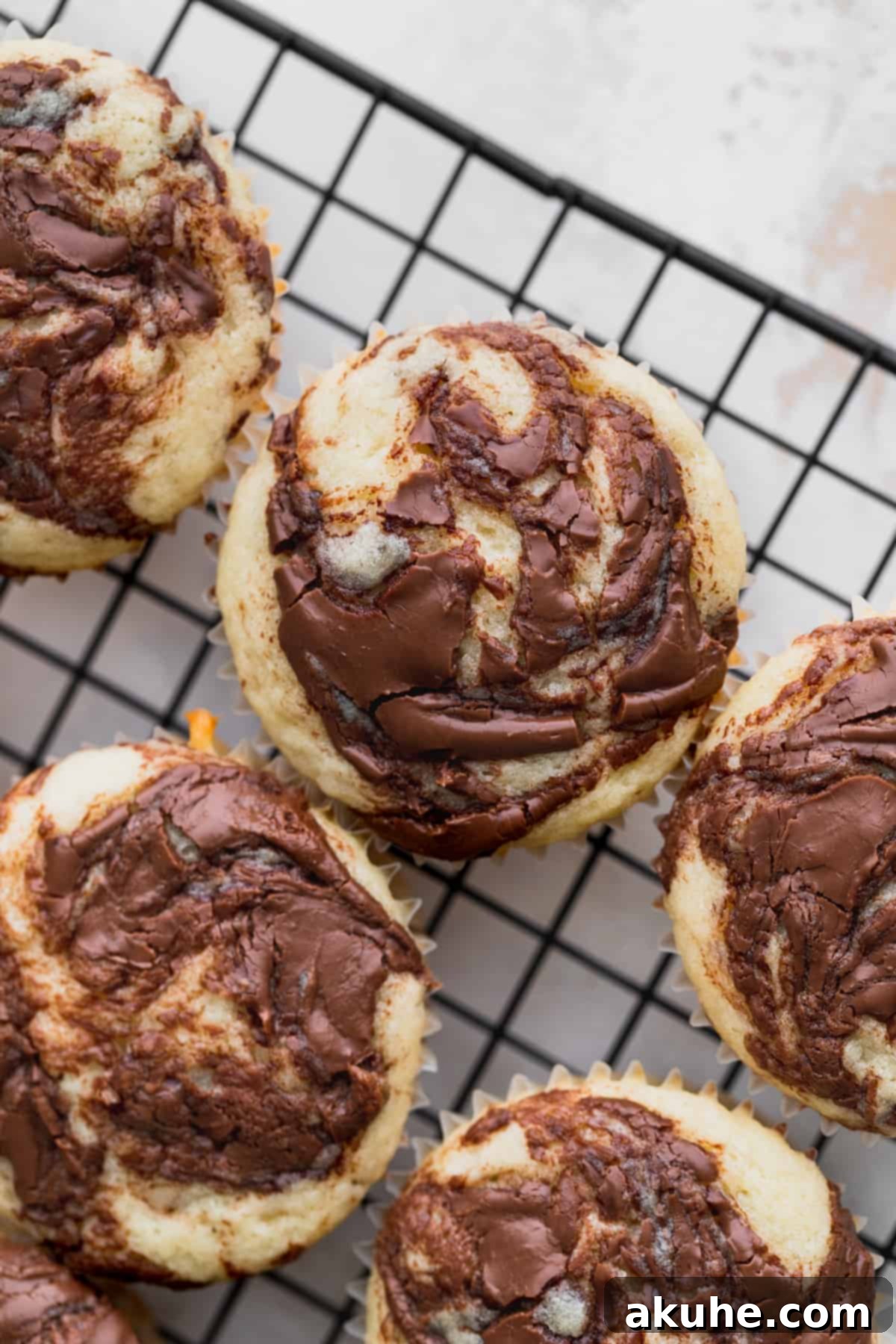 Irresistible Vanilla Nutella Cupcakes 9 Freshly baked vanilla cupcakes resting on a wire cooling rack, patiently awaiting their decadent frosting.