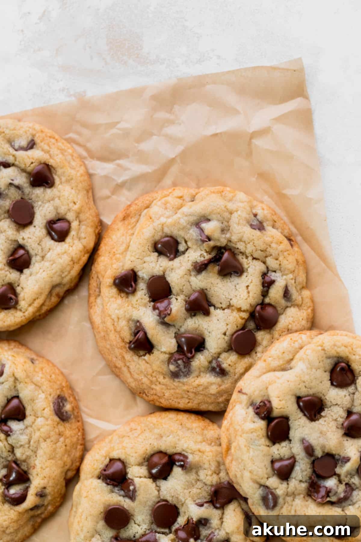 Just Enough Chocolate Chip Bliss 2 Freshly baked small batch chocolate chip cookies on a sheet of parchment paper, showcasing their golden brown edges and gooey chocolate.