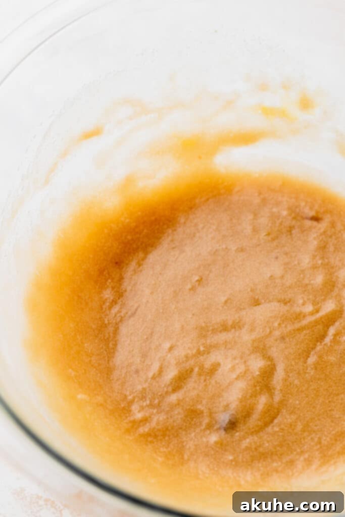 Just Enough Chocolate Chip Bliss 4 Wet ingredients (melted butter, sugars, vanilla, egg) in a glass mixing bowl, thoroughly combined.