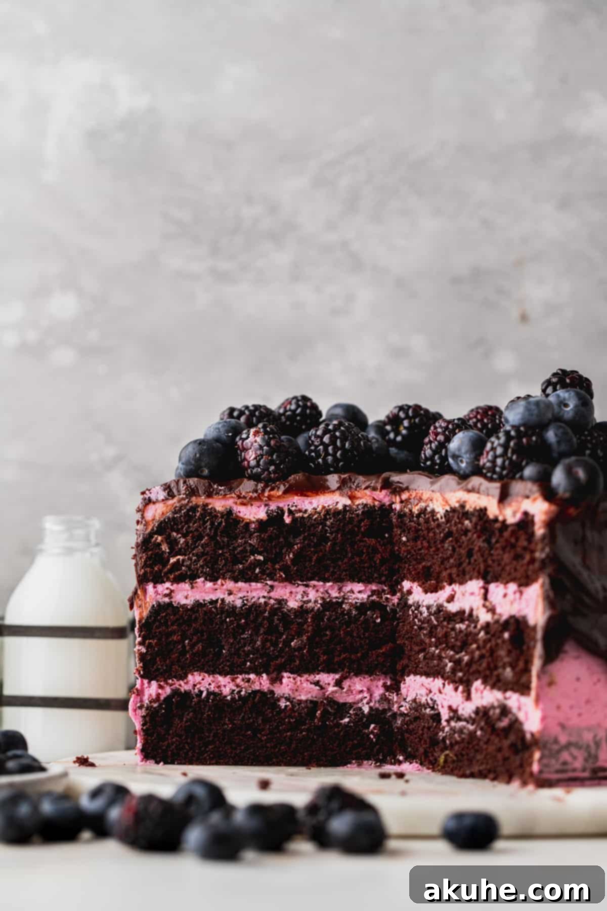Blueberry Chocolate Layer Cake 2 A stunning three-layer blueberry chocolate cake, perfectly sliced to reveal its moist interior and vibrant lemon-blueberry frosting. Garnished with fresh blueberries and blackberries, it promises a delightful sensory experience.