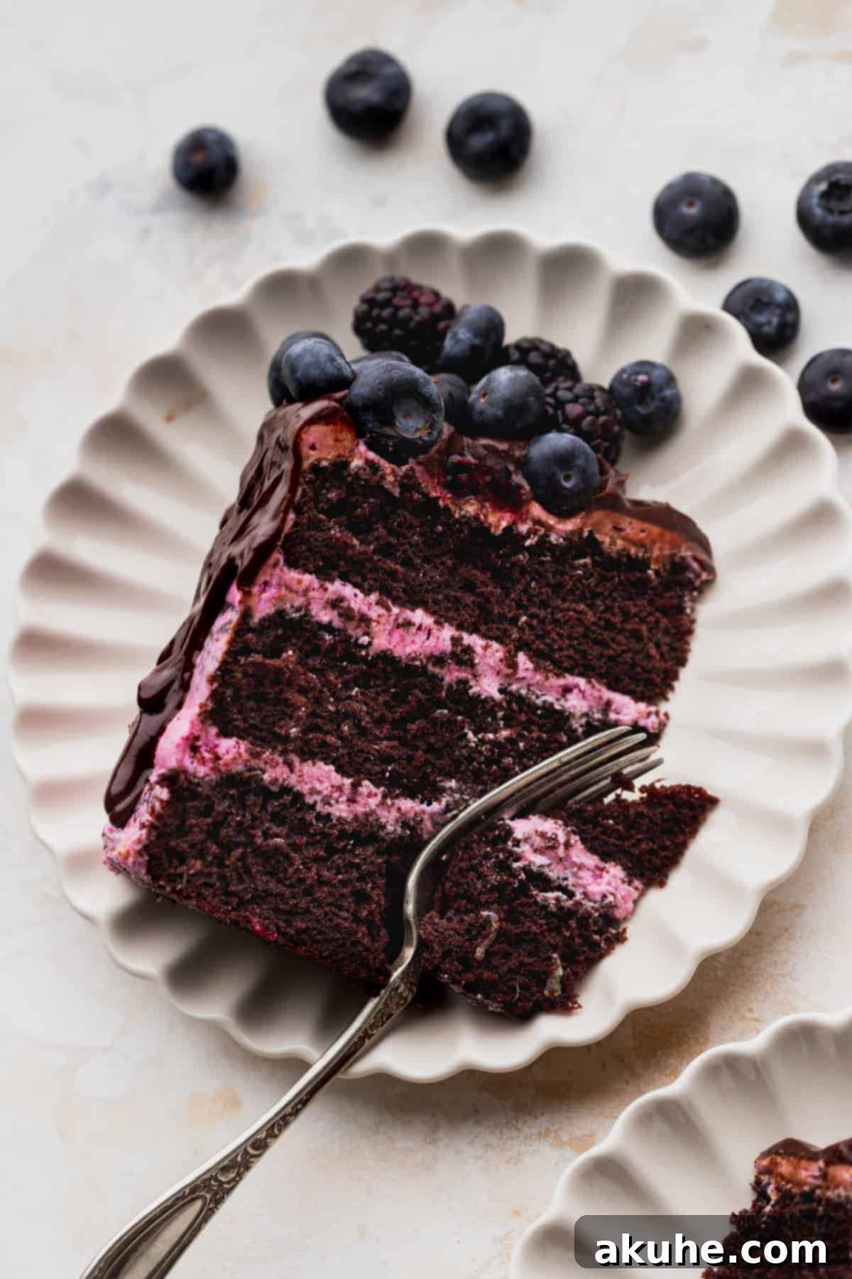 Blueberry Chocolate Layer Cake 11 A single, perfectly cut slice of layered blueberry chocolate cake, garnished with fresh berries and ready to be savored.