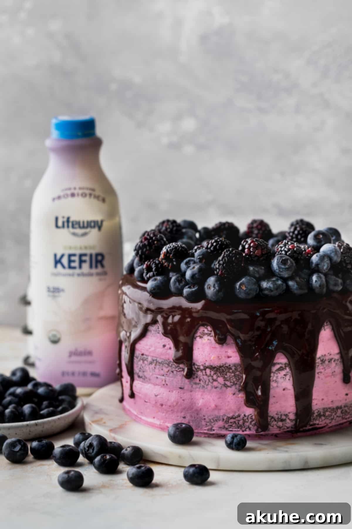 Blueberry Chocolate Layer Cake 3 A beautifully decorated layered blueberry chocolate cake resting on a pristine marble board, showcasing the intricate details of its frosting and fresh berry toppings.