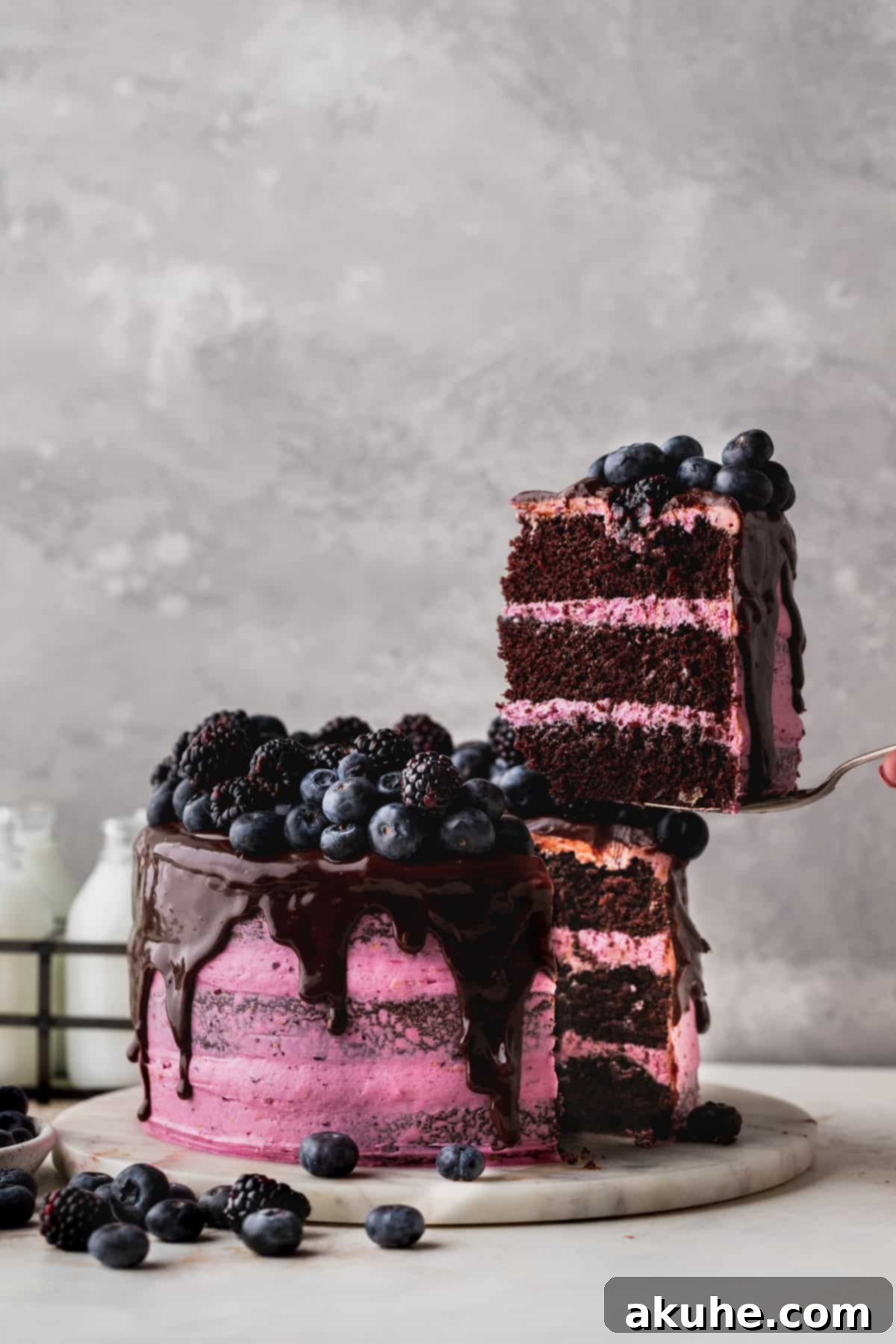 Blueberry Chocolate Layer Cake 10 A hand gently pulling a perfect slice of blueberry chocolate cake from the whole, ready to be served and enjoyed.