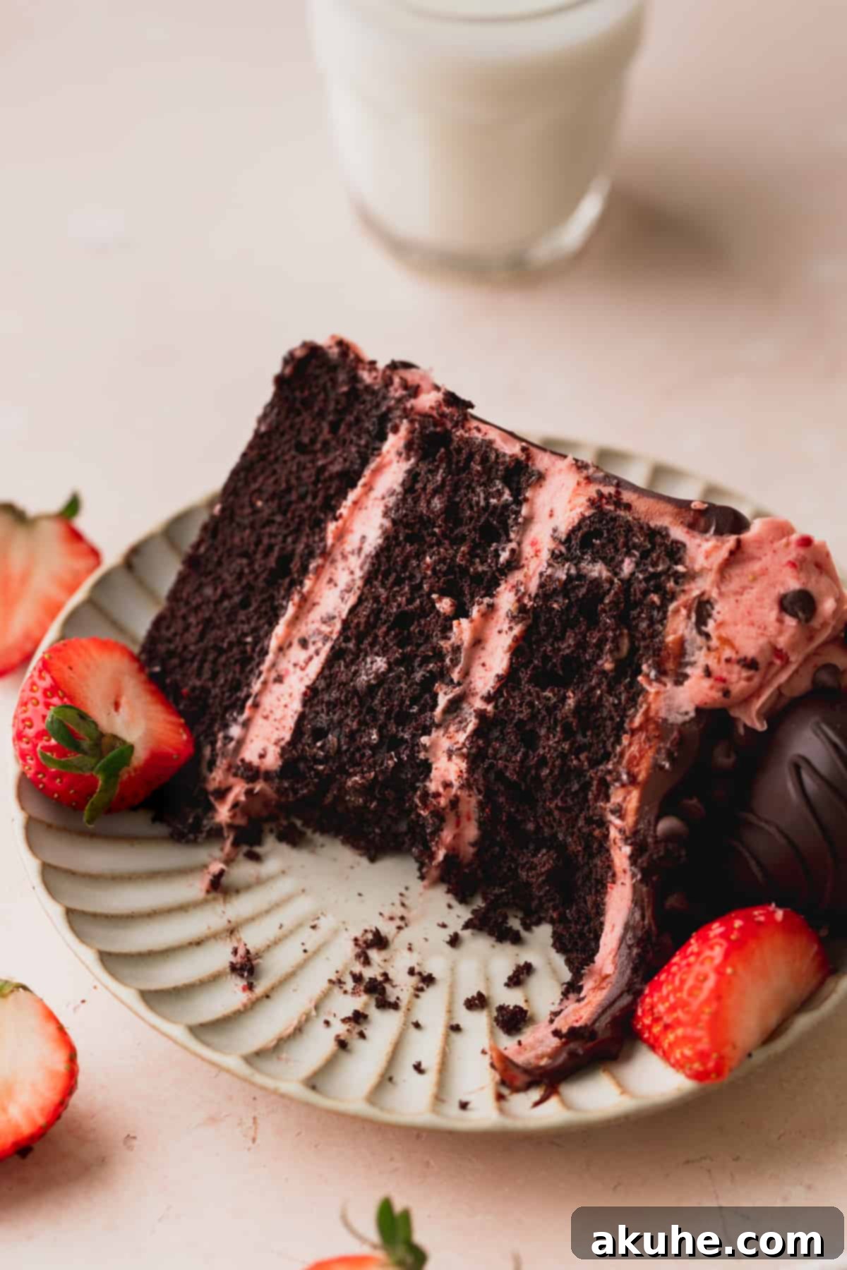 A slice of chocolate covered strawberry cake on a plate with a bite taken, showing its irresistible texture.