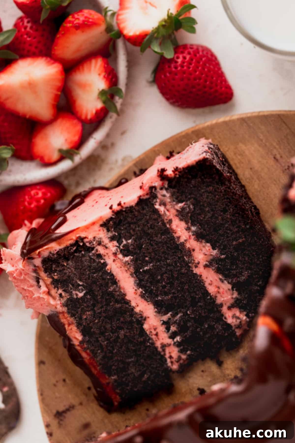 A perfectly cut slice of Chocolate Covered Strawberry Cake on a wooden board, showcasing the moist layers and rich frosting.