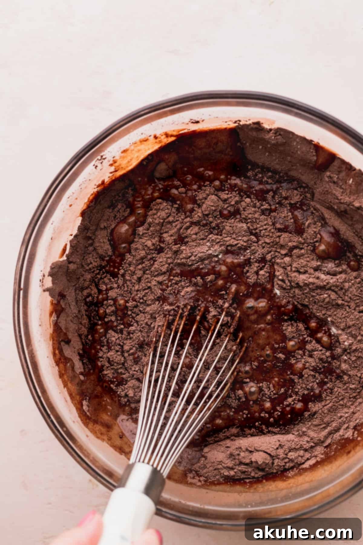 Mixing wet ingredients for the chocolate cake in a clear glass bowl.