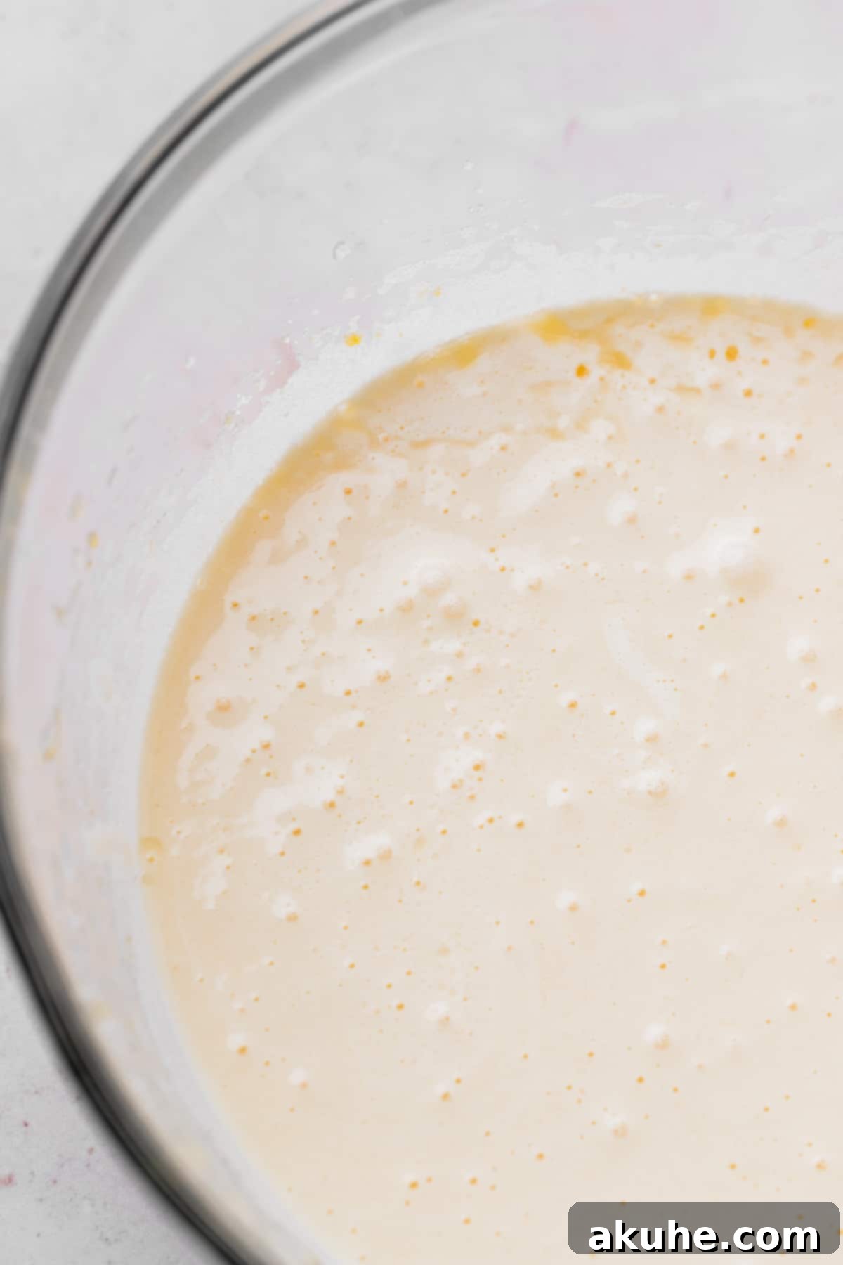 Beaten eggs and sugar in a glass bowl.