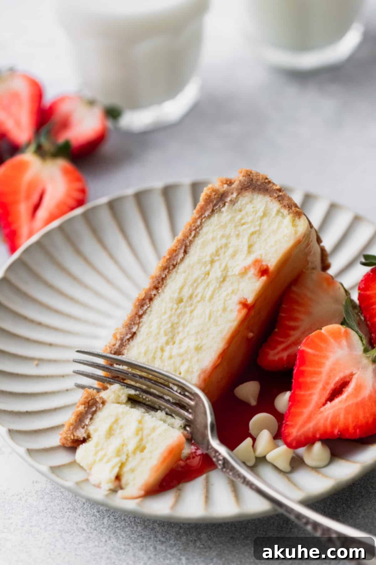 Decadent White Chocolate Cheesecake 13 A delectable slice of white chocolate cheesecake on a plate, with a fork gently inserted, ready to be enjoyed.