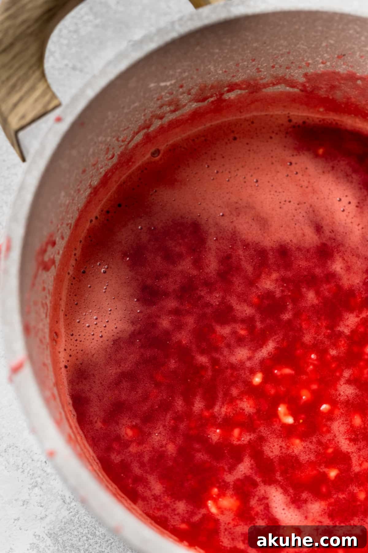 Decadent White Chocolate Cheesecake 10 Rich, glossy strawberry glaze simmering in a pot, ready to thicken.