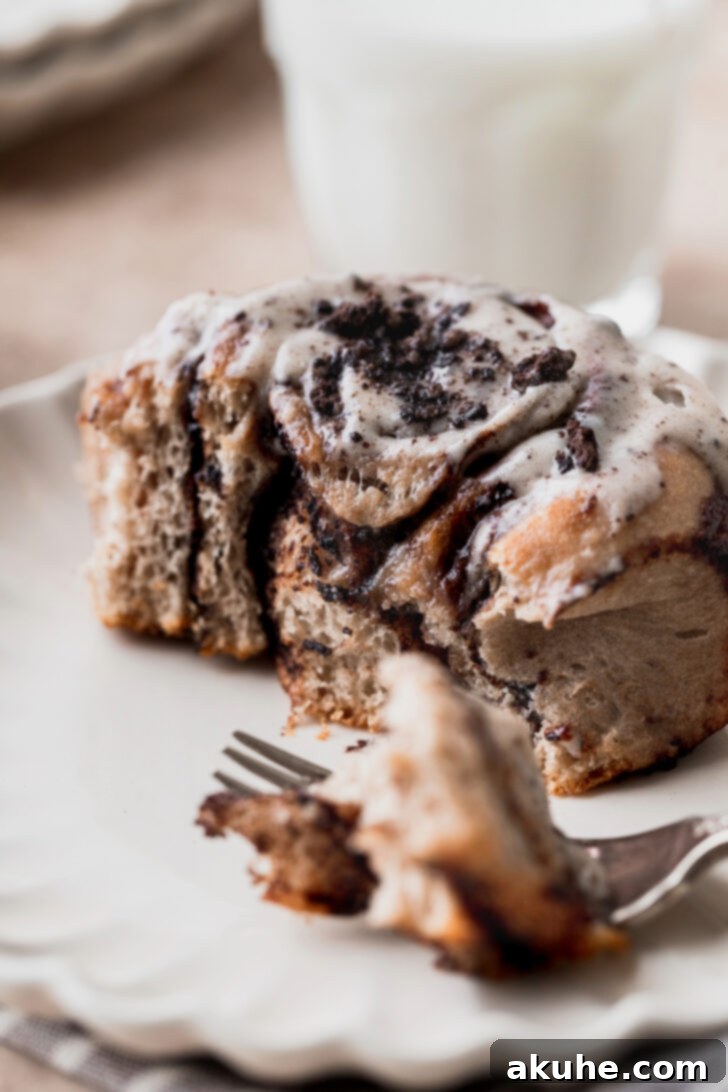 A close-up of an Oreo cinnamon roll with a bite taken out, revealing the swirled filling and soft texture.