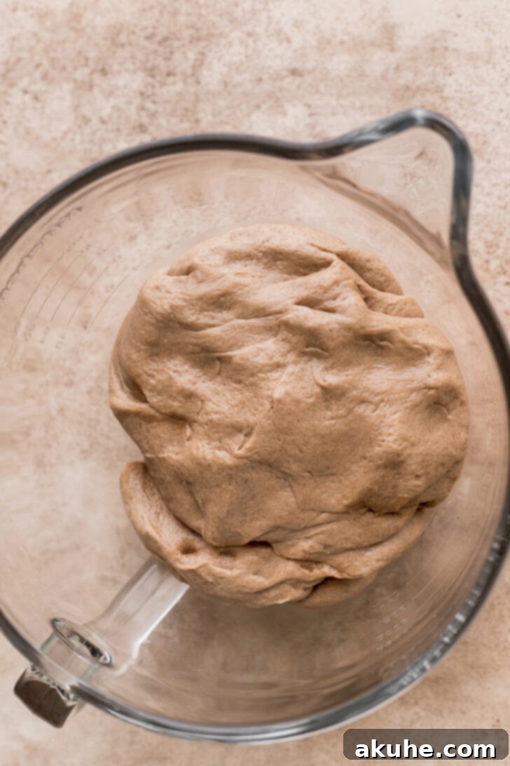 Soft, dark brown dough rising in a bowl, speckled with Oreo crumbs.