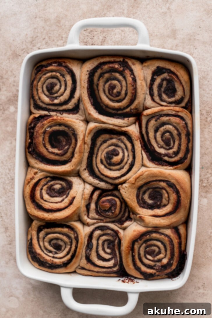 Warm, baked Oreo cinnamon rolls covered in a smooth, white Oreo cream cheese glaze, melting into the swirls.