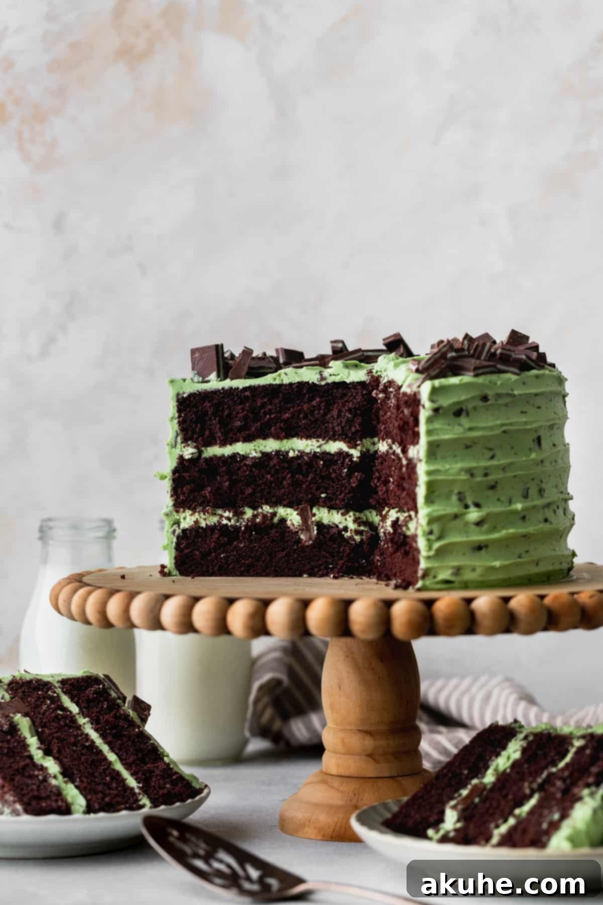 Andes Mint Chocolate Cake 2 Chocolate mint cake on a cake stand with cake slices around it.