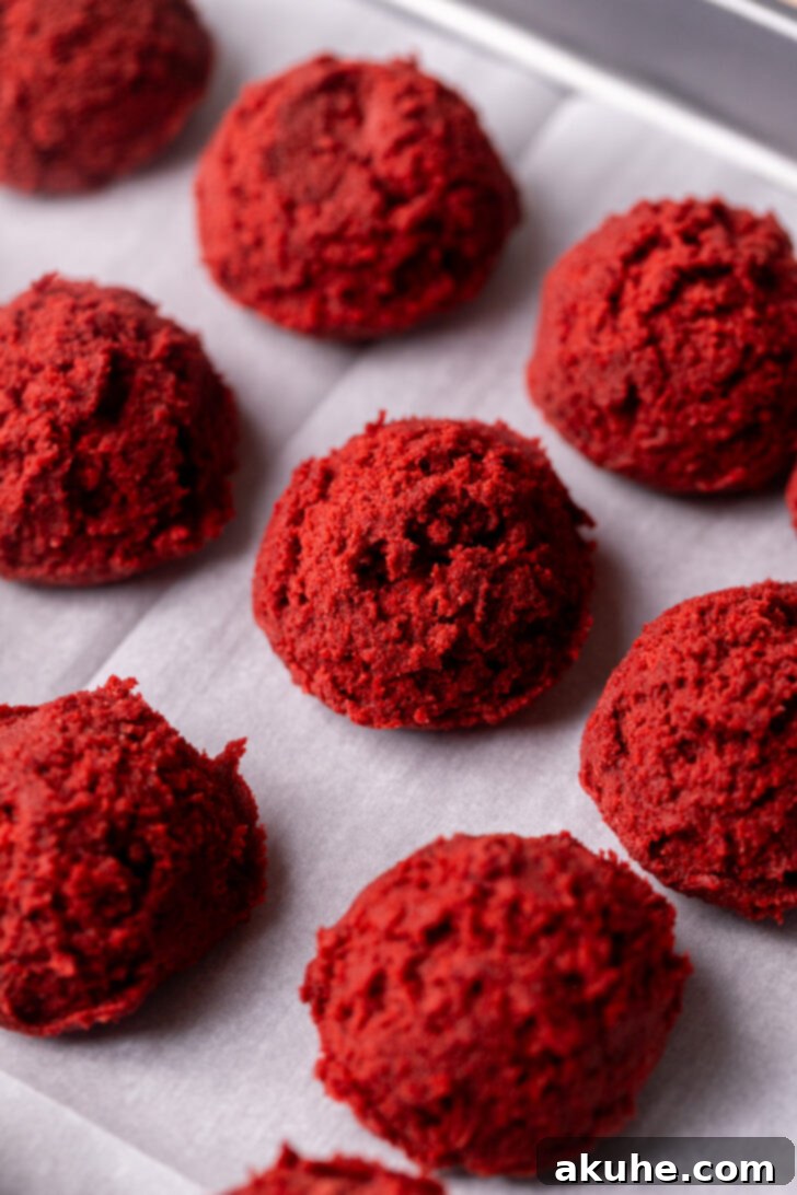 Red Velvet Cookie Delights 5 Cookie dough balls on a cookie sheet.