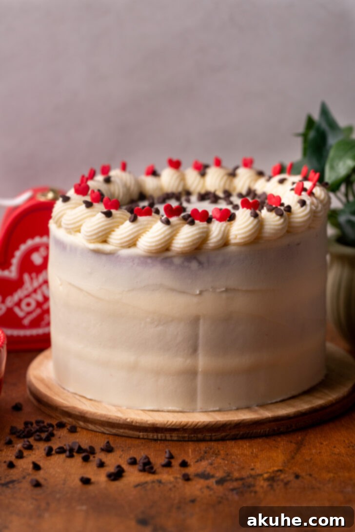 A fully decorated Red Velvet Chocolate Chip Cake on a wooden board.
