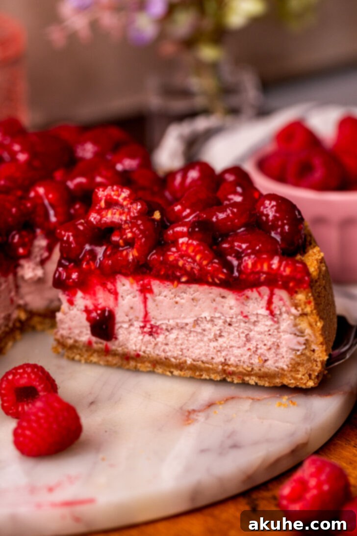 A tempting slice being cut from the raspberry cheesecake, showcasing its creamy texture and vibrant colors.